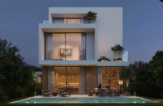 Rear view of a modern villa at Chevalia Estate 2, showing the backyard with a swimming pool and illuminated patio area at dusk.