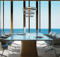 Modern conference room with marble table, stylish chairs, and panoramic ocean view through floor-to-ceiling windows.