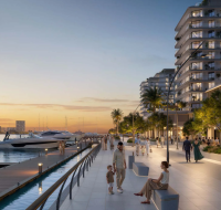The illuminated waterfront promenade at AUREA by EMAAR, showing residents strolling along at sunset.