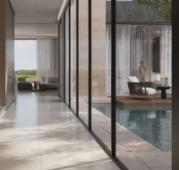 Modern villa entry hall next to an outdoor pool deck with lounge chairs and a view into the living room.