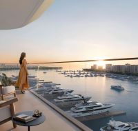 Modern residential building overlooking a marina filled with boats at sunset