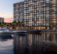 Modern high-rise building alongside a bustling marina with docked yachts.