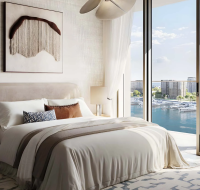 Modern bedroom with balcony overlooking a waterfront filled with yachts.