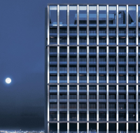 Modern high-rise building illuminated under a moonlit sky with panoramic city views
