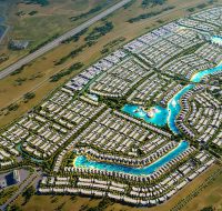 Aerial view of a massive residential master community with numerous villas organized around a large, winding blue lagoon.