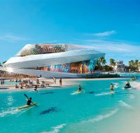 Tropical community beach area with turquoise water, palm trees, and a distinctive piece of architectural art.