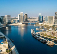 An urban waterfront with floating villas and yachts, framed by high-rise residential buildings under a blue sky.