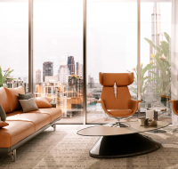 Modern living room with leather furniture, a unique coffee table, and a panoramic window overlooking a city skyline.