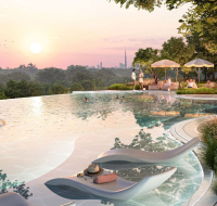 Infinity pool at sunset with lounge chairs, people swimming, and city skyline in the distance.