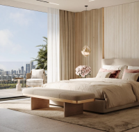 Bright interior space with a large bed, lounge chairs, and a view of skyscrapers, including the Burj Khalifa.