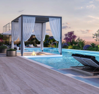 Elegant rooftop pool with cabanas, lounge chairs, and fire feature at sunset