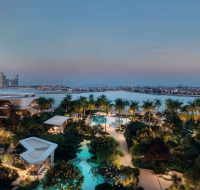 Waterfront view with landscaped gardens and pools at sunset