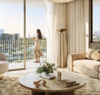 Elegant living room with sofa, armchair, and coffee table, plus a woman on the balcony enjoying city views.