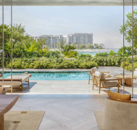 Contemporary apartment terrace with floor-to-ceiling glass doors opening onto a pool and sun loungers.
