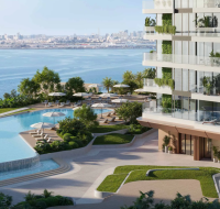 Infinity-edge pool with a waterfall, overlooking the sea and city skyline, beside a modern glass high-rise.