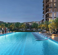 The long, resort-style swimming pool amenity designed by Emaar , featuring submerged lounge chairs and ambient lighting at dusk.